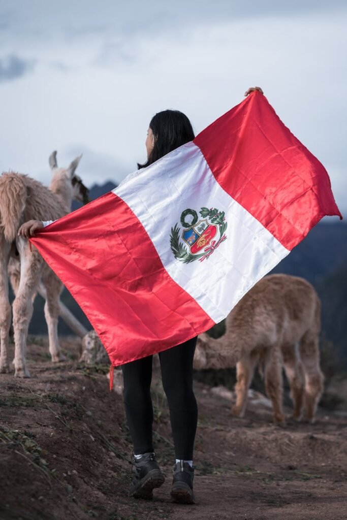 brunette woman with peruvian flag standing by animals